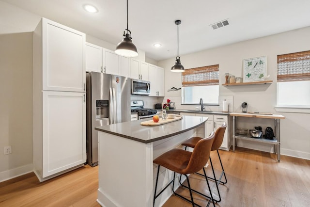2827 Manor Rd Unit 3104, Austin, TX 78722 - kitchen with stainless steel appliances, light wood-type flooring, a kitchen breakfast bar, white cabinetry, and a center island