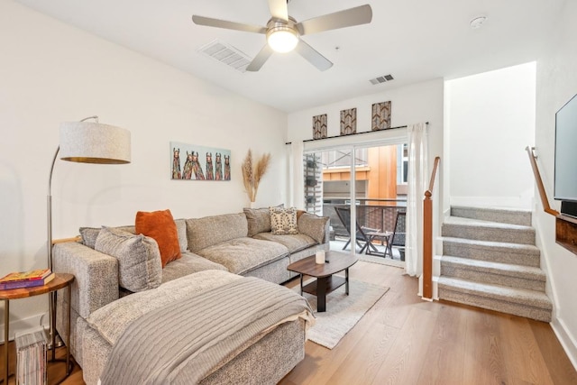 living area with a ceiling fan, visible vents, stairway, and wood finished floors