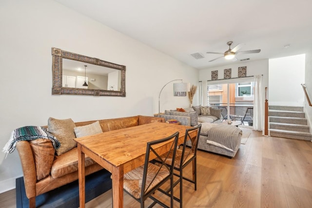 dining room with ceiling fan, stairs, visible vents, and wood finished floors