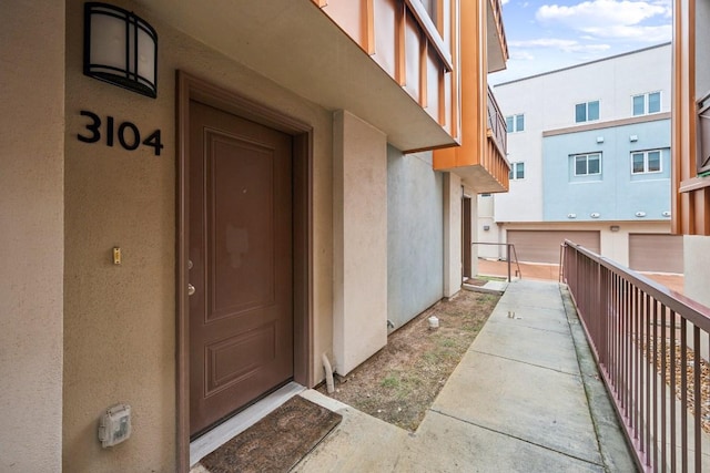 entrance to property featuring a balcony and stucco siding