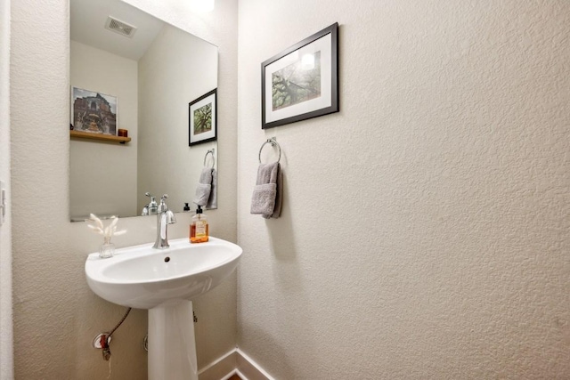 bathroom featuring visible vents and a textured wall