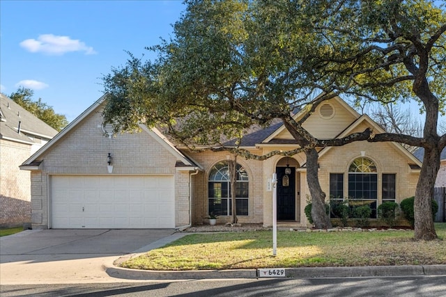 view of front of home featuring a garage, driveway, brick siding, and a front yard