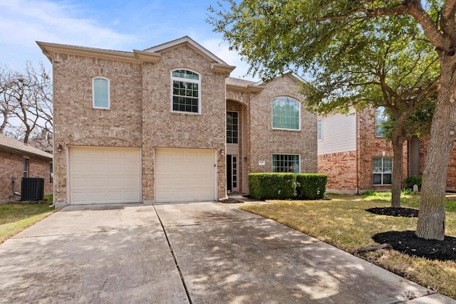 traditional-style home with central AC unit, an attached garage, brick siding, concrete driveway, and a front yard