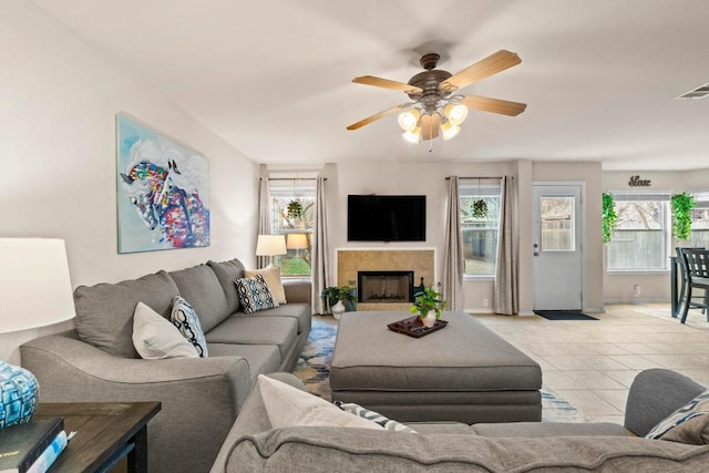 living room with a fireplace, visible vents, light tile patterned flooring, ceiling fan, and baseboards