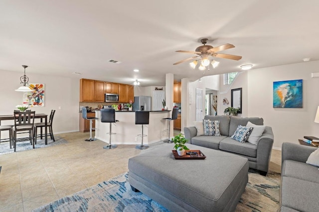 living room with light tile patterned floors, ceiling fan, visible vents, and baseboards