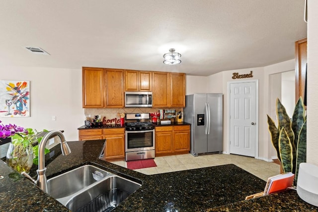 kitchen with appliances with stainless steel finishes, brown cabinetry, a sink, and tasteful backsplash