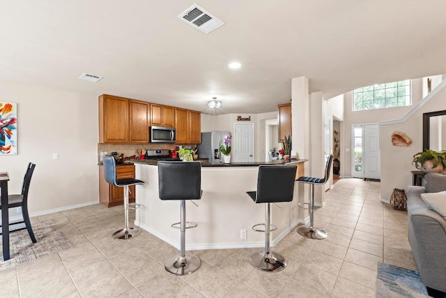 kitchen featuring dark countertops, appliances with stainless steel finishes, visible vents, and a kitchen breakfast bar