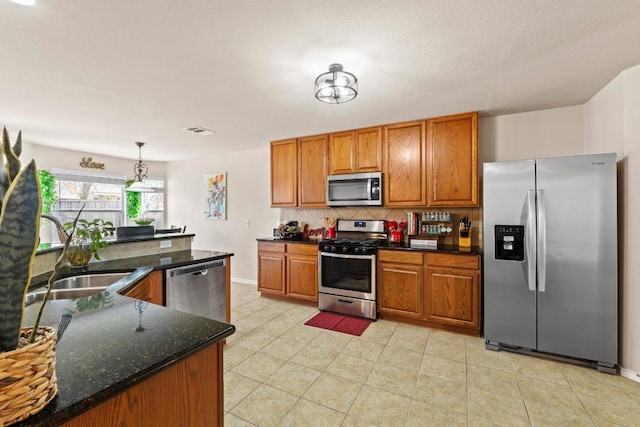 kitchen featuring a sink, visible vents, appliances with stainless steel finishes, backsplash, and brown cabinetry