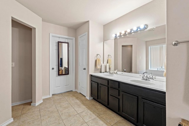 full bathroom with double vanity, a sink, baseboards, and tile patterned floors