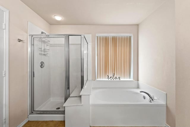 bathroom featuring a garden tub and a shower stall