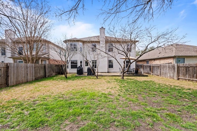 rear view of house with a fenced backyard, a yard, and a chimney