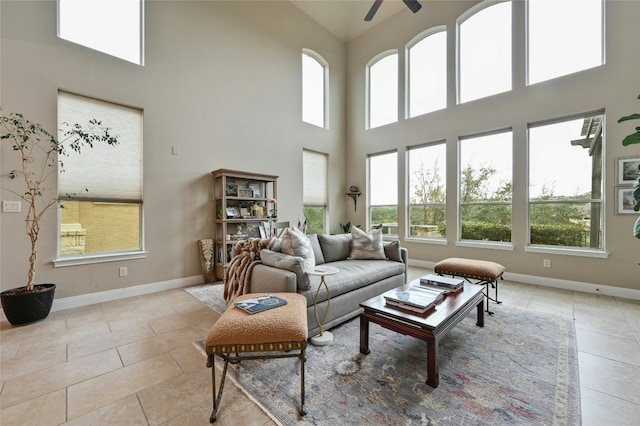 tiled living room featuring a high ceiling, baseboards, and a ceiling fan