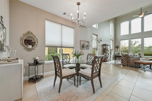 dining space featuring light tile patterned floors, ceiling fan with notable chandelier, a towering ceiling, visible vents, and baseboards