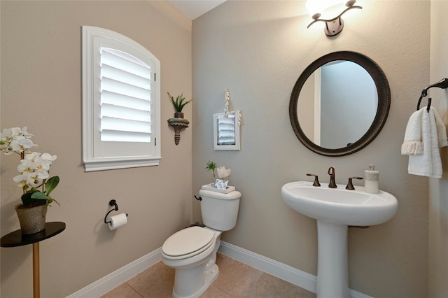 bathroom featuring baseboards, a sink, toilet, and tile patterned floors