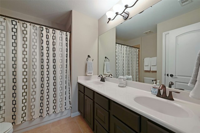 bathroom featuring toilet, tile patterned flooring, and a sink