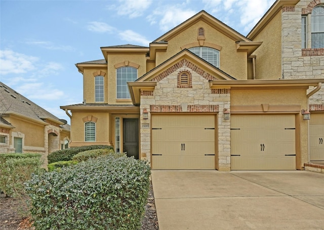 view of front facade featuring a garage, stone siding, concrete driveway, and stucco siding