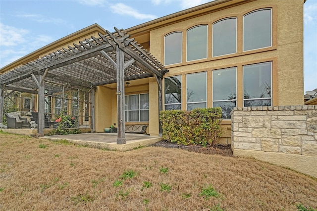 back of house featuring a patio area, a pergola, and stucco siding