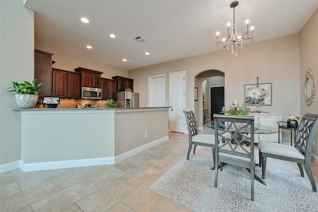 kitchen featuring stone countertops, arched walkways, hanging light fixtures, stainless steel appliances, and a notable chandelier