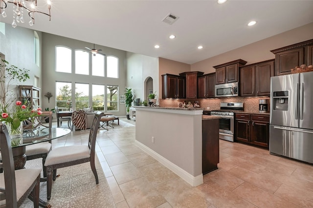 kitchen with tasteful backsplash, visible vents, appliances with stainless steel finishes, dark brown cabinets, and ceiling fan with notable chandelier