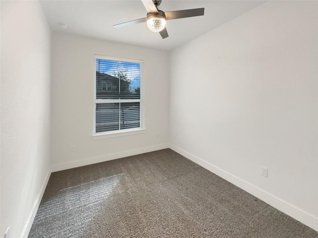 spare room with ceiling fan, baseboards, and dark carpet