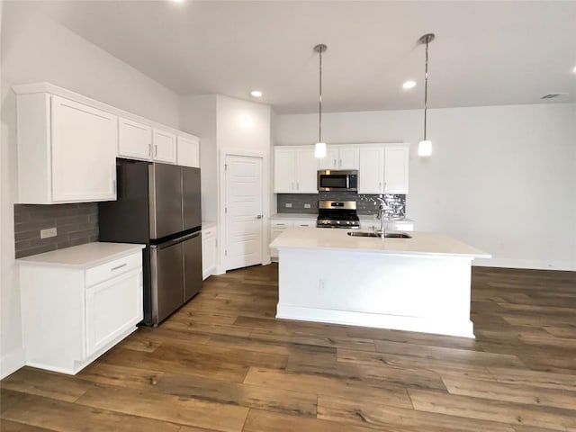 kitchen featuring tasteful backsplash, dark wood finished floors, appliances with stainless steel finishes, white cabinetry, and a sink