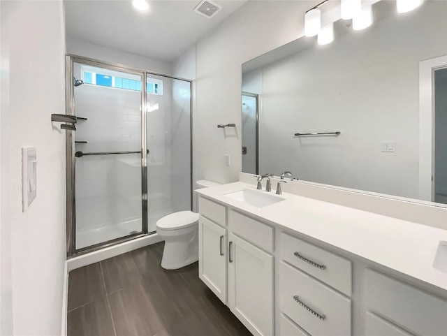 bathroom with a stall shower, visible vents, vanity, and toilet