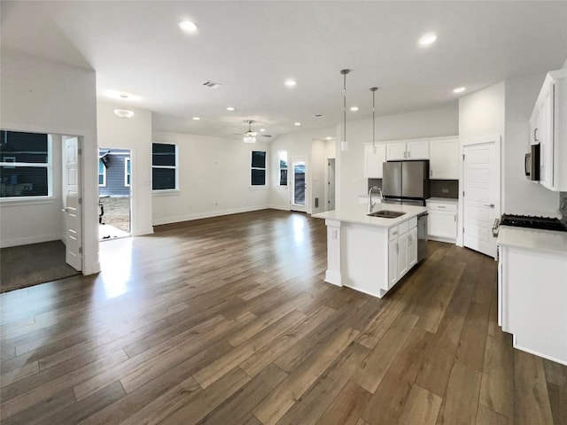 kitchen featuring dark wood-style flooring, appliances with stainless steel finishes, a ceiling fan, open floor plan, and a sink