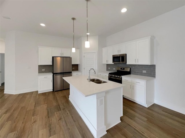 kitchen with an island with sink, dark wood-type flooring, stainless steel appliances, and a sink