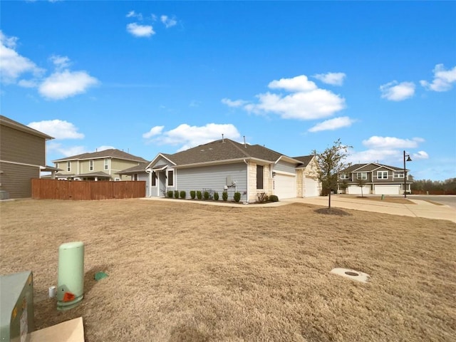 view of front of home featuring a garage, a front yard, driveway, and fence