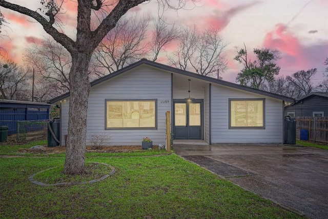 view of front of house with french doors, a yard, and fence