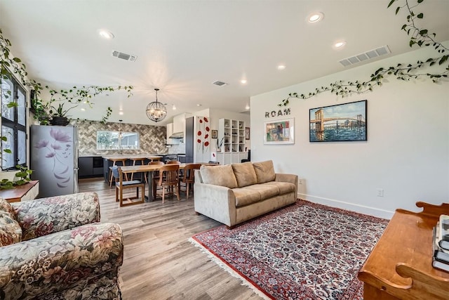 living room featuring light wood-type flooring, visible vents, and recessed lighting