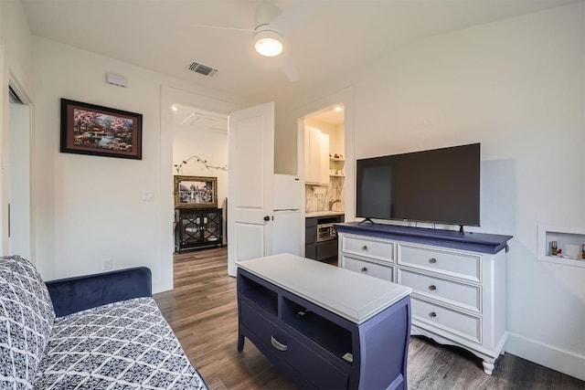 living room with ceiling fan, dark wood-type flooring, visible vents, and baseboards