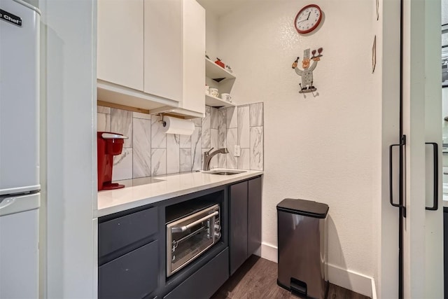 kitchen with refrigerator, tasteful backsplash, light countertops, white cabinetry, and a sink