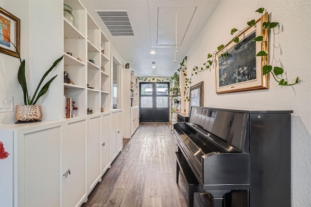 living area featuring attic access, visible vents, wood finished floors, and french doors