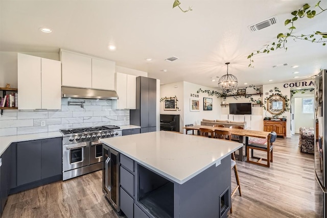 kitchen with under cabinet range hood, visible vents, range with two ovens, and light countertops