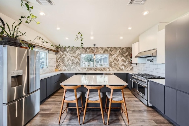 kitchen featuring visible vents, appliances with stainless steel finishes, breakfast area, a breakfast bar area, and under cabinet range hood