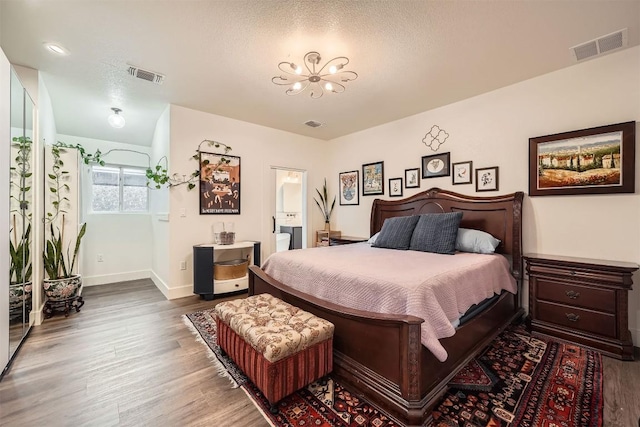 bedroom featuring an inviting chandelier, baseboards, visible vents, and wood finished floors