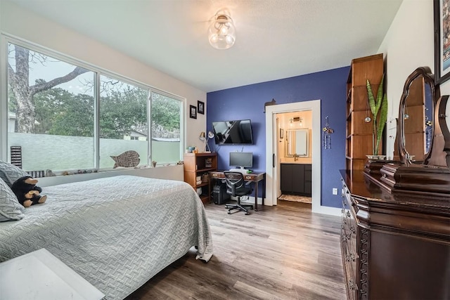 bedroom featuring wood finished floors, connected bathroom, and baseboards