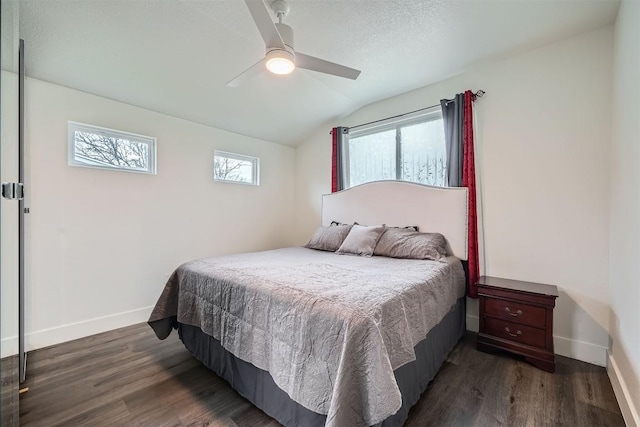 bedroom with dark wood-type flooring, vaulted ceiling, baseboards, and a ceiling fan