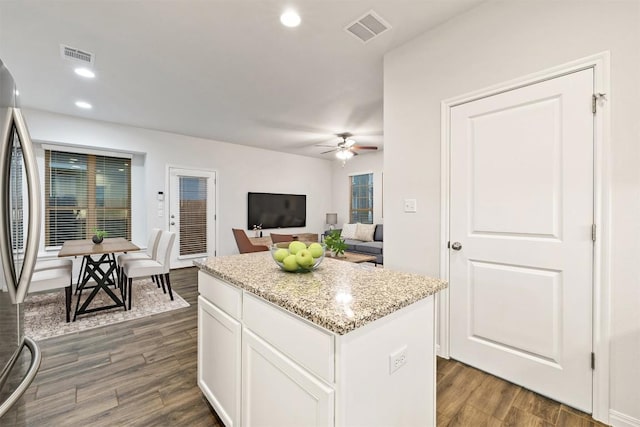 kitchen featuring dark wood finished floors, visible vents, stainless steel fridge, and a center island