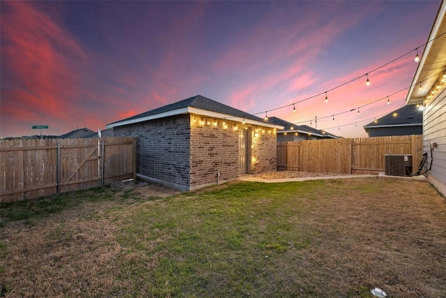 yard at dusk featuring cooling unit and a fenced backyard