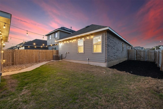 back of property featuring central air condition unit, a lawn, and a fenced backyard