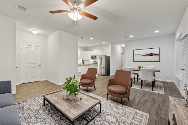 living area with recessed lighting, visible vents, baseboards, and wood finished floors