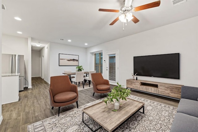 living area featuring a ceiling fan, visible vents, baseboards, light wood-style flooring, and recessed lighting