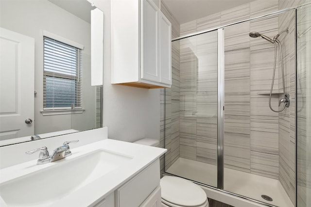 bathroom with a stall shower, toilet, and vanity