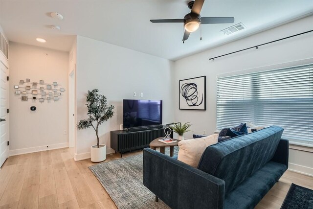 living area with baseboards, a ceiling fan, visible vents, and light wood-style floors