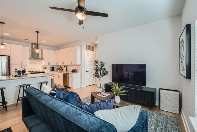 living area with ceiling fan, light wood-style flooring, and visible vents