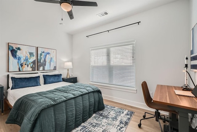 bedroom featuring a ceiling fan, visible vents, baseboards, and wood finished floors