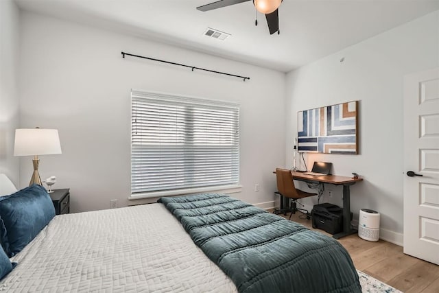 bedroom featuring light wood-style flooring, a ceiling fan, visible vents, and baseboards