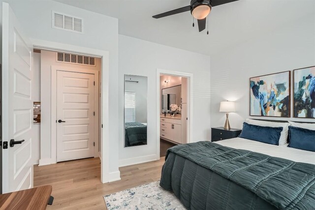 bedroom with light wood finished floors, connected bathroom, visible vents, and baseboards